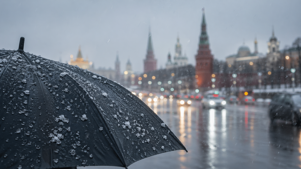 Черный зонт с каплями воды и тающим снегом.