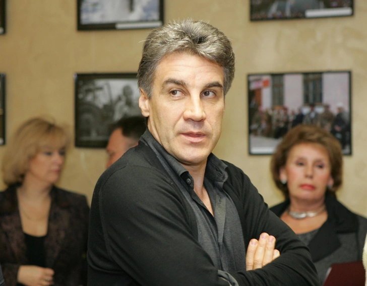 Алексей на фоне людей и фотографий.